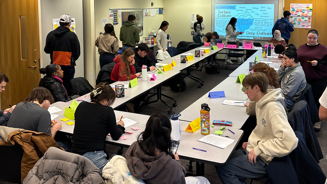 ALA 240 students work in groups around tables during a class activity on community well-being.