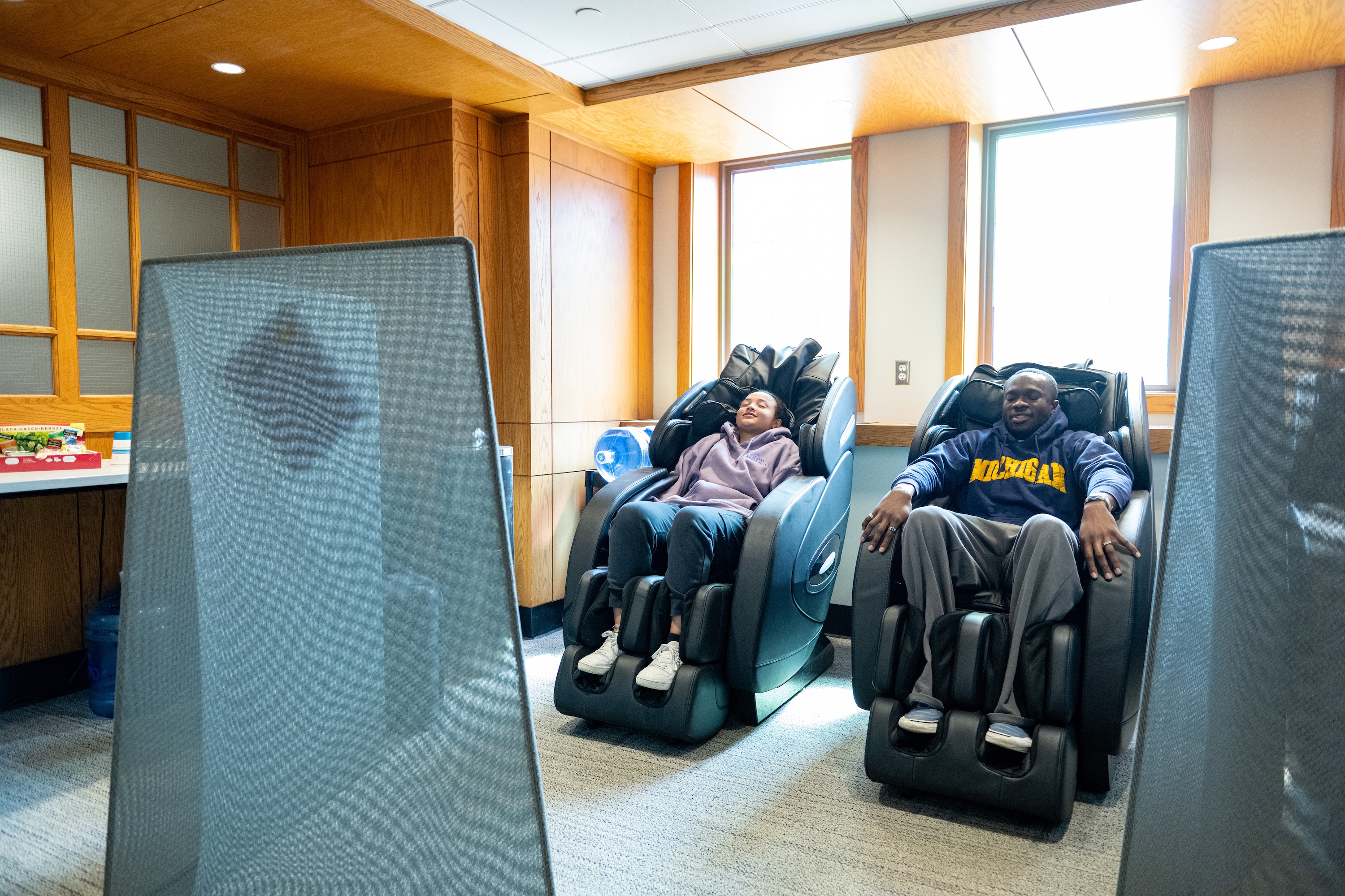 Two students laying down on the massage chairs in the Michigan Union.