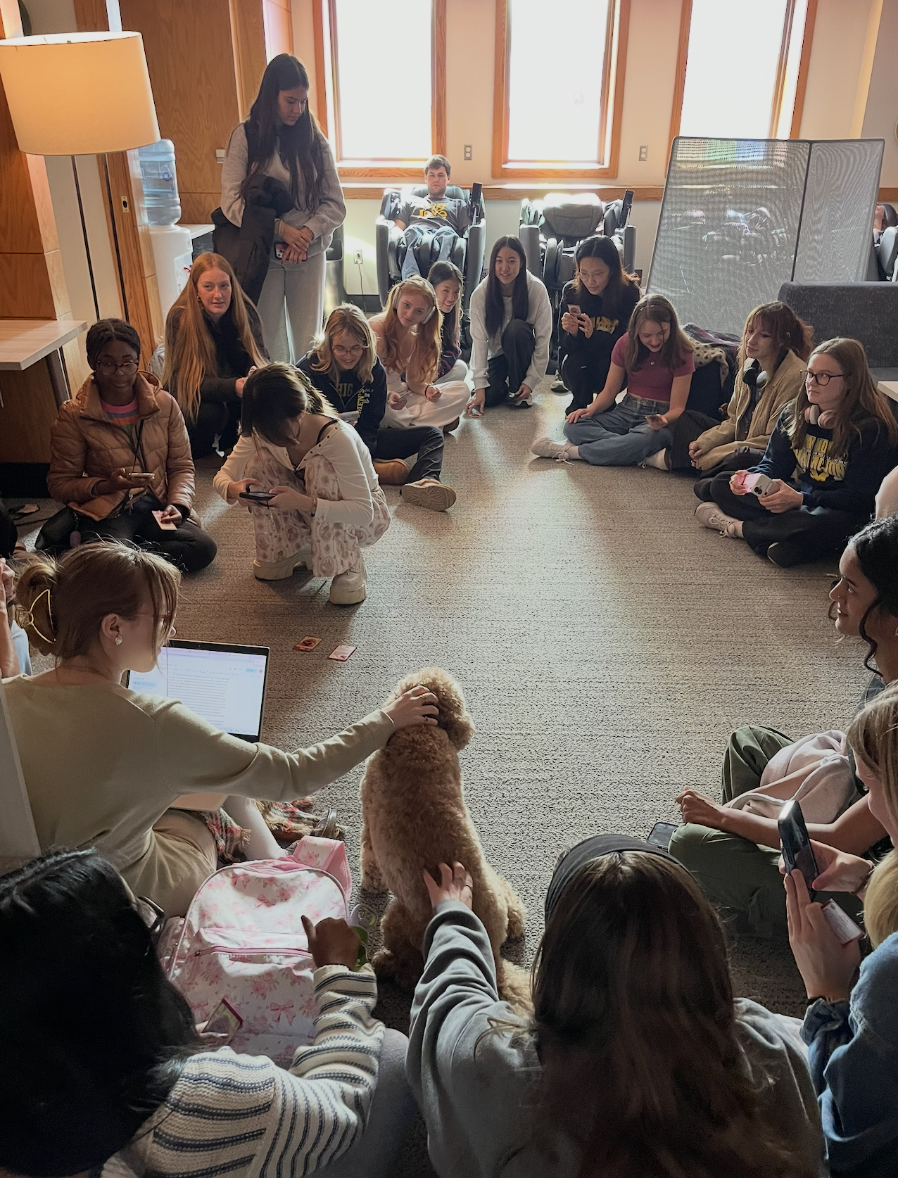 Gus the therapy dog is surrounded by students in the Welless Zone during a visit.