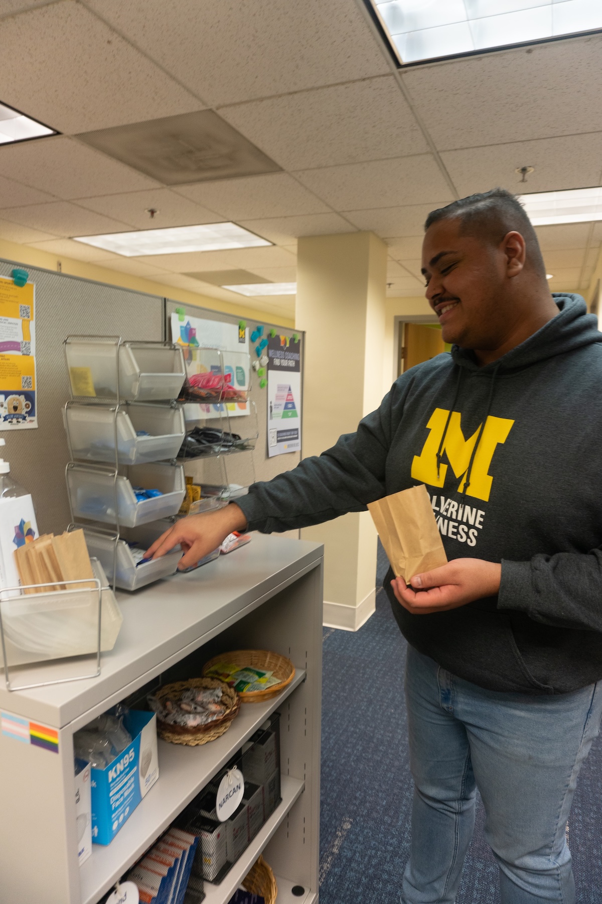 Student grabbing sexual wellness supplies into a paper bag. 